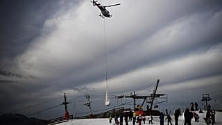 Urlauber schauen der Schnee-Lieferung in Superbagneres zu.