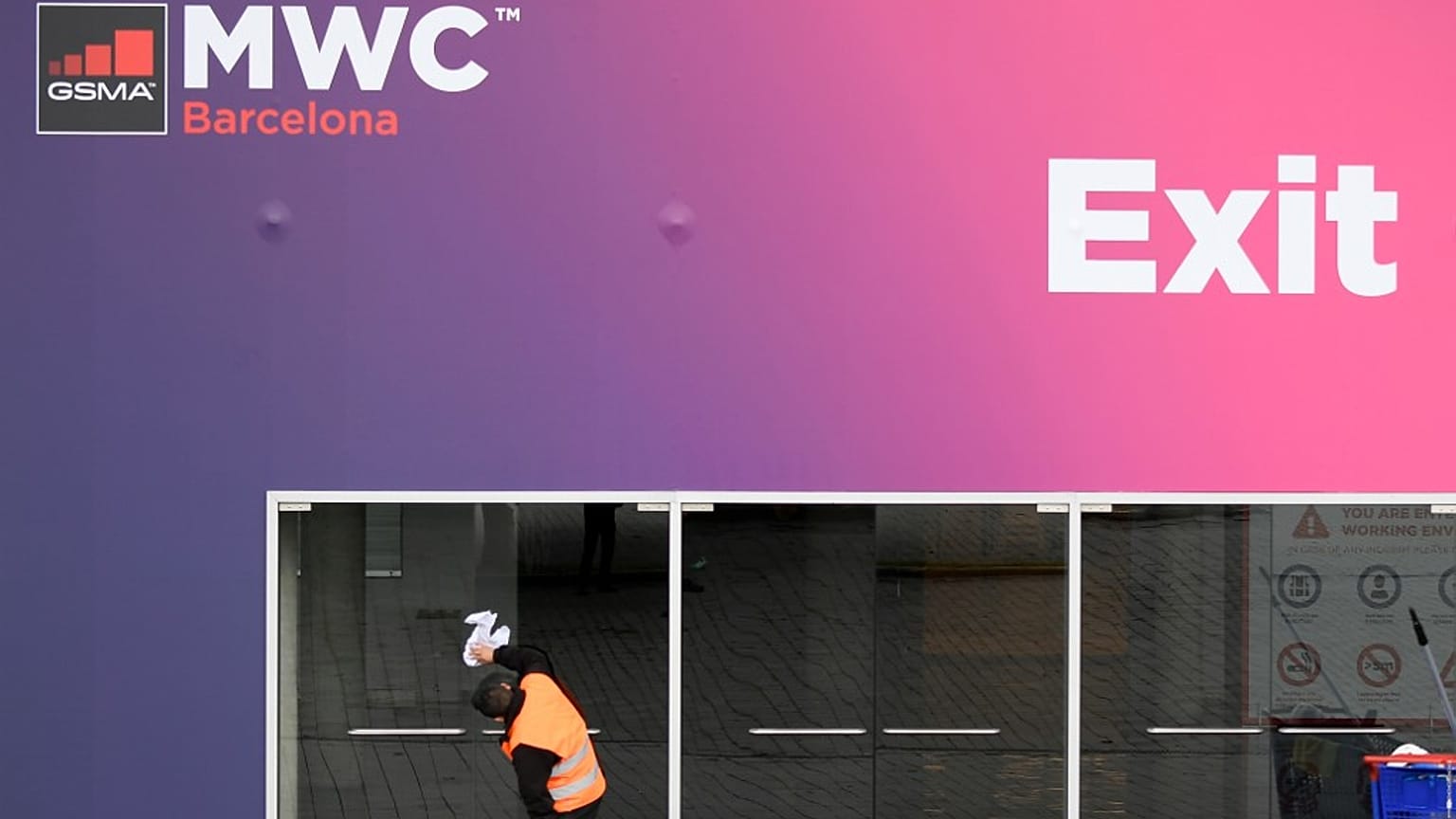 Un trabajador limpia las puertas de cristal en la sede del Congreso Mundial Móvil del CMM el 12 de febrero de 2020 en el centro Montjuic de Fira Barcelona en Barcelona.