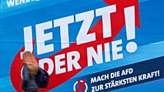A woman walks in front of a campaign poster of the far-right Alternative for Germany (AFD) in Erfurt, Germany, Friday, Oct. 25, 2019