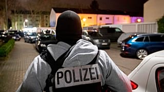 A police officer guards the road in front of a house that is searched through by police in Hanau, Germany Thursday, Feb. 20, 2020. (AP Photo/Michael Probst)