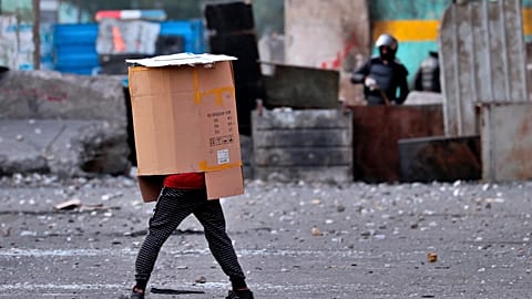 A protester covers his body while security force use slingshots to disperse anti-government protesters during clashes in downtown Baghdad, Iraq