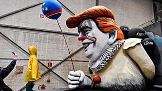 A man takes a picture of a satiric carnival float during a preview in a hall in Cologne, Germany.