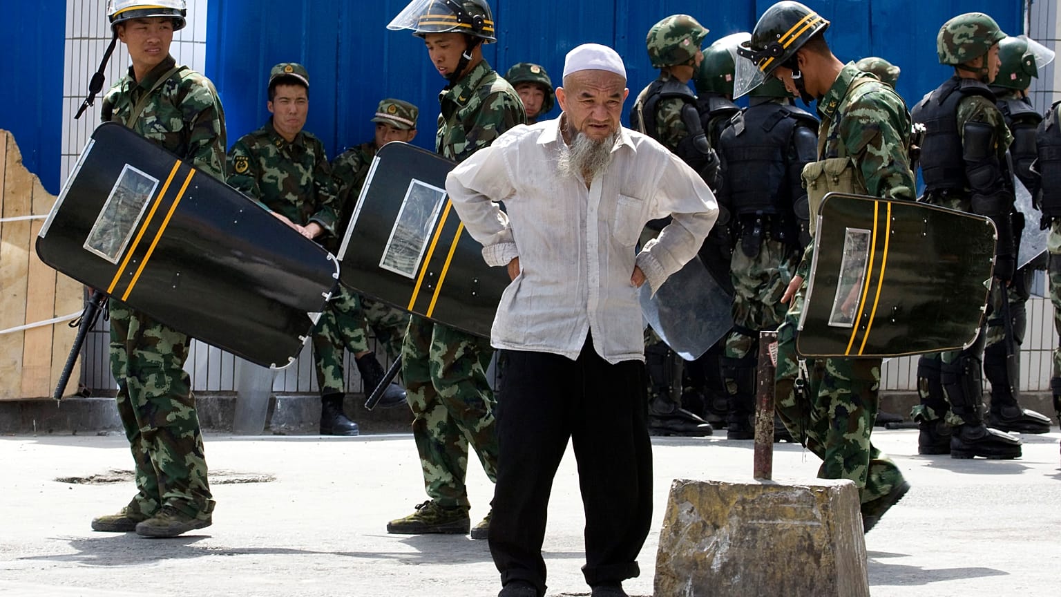 July 8, 2009, file photo, paramilitary police walk past an elderly ethnic minority man in Urumqi, western China's Xinjiang region. 
