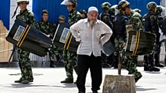 July 8, 2009, file photo, paramilitary police walk past an elderly ethnic minority man in Urumqi, western China's Xinjiang region. 