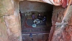 Members of a family of internally displaced Syrians eat together in an underground shelter where several families from Aleppo and Idlib provinces are taking refuge.