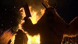 Creature in sheepskin cloak watches coffin representing winter burn