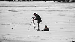 A man filming on a snowy backdrop.