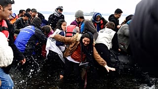 Migrants arrive with a dinghy at the village of Skala Sikaminias, on the Greek island of Lesbos, after crossing the Aegean sea from Turkey, on Friday, Feb. 28