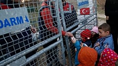 Um trabalhador de ONG distribui leite para crianças na fronteira entre a Turquia e a Grécia