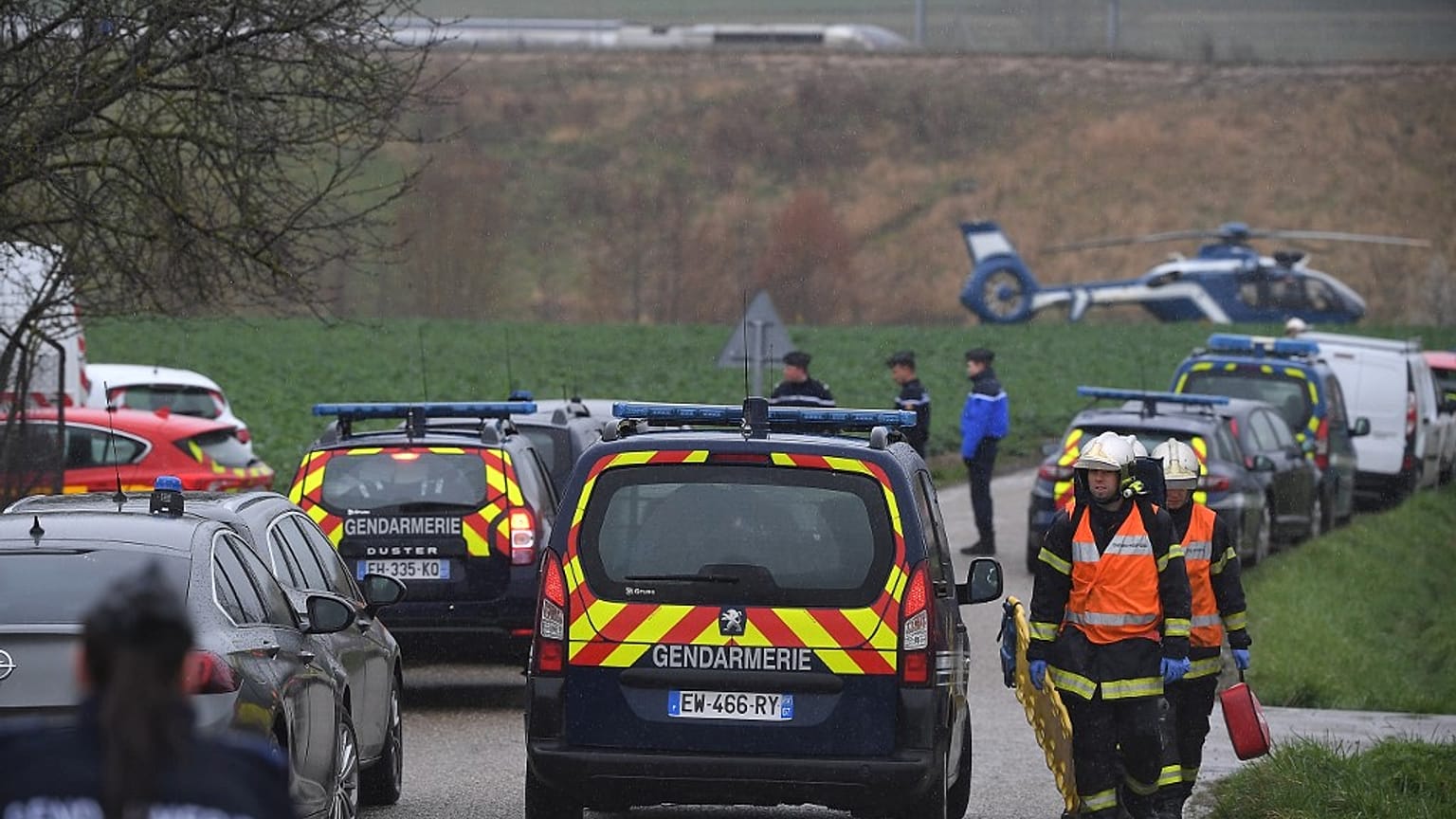 Gendarmes and firefighters gather at the site where a high-speed TGV train locomotive derailed 