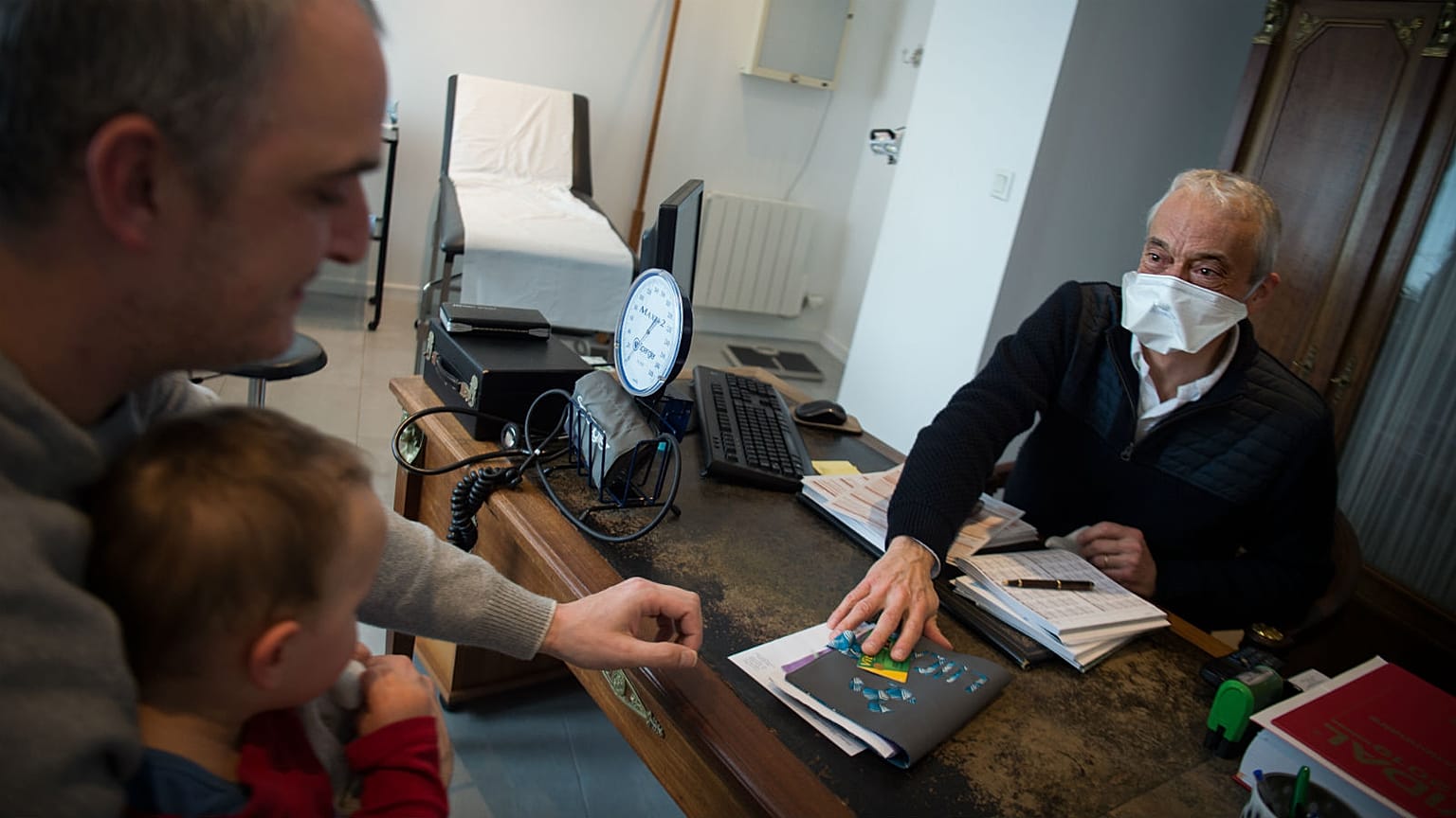 A family doctor in France wears a protective face mask as a preventive measure against the spread of COVID-19