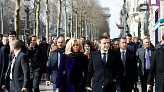 French President Emmanuel Macron and his wife Brigitte Macron walk down the Champs-Elysees avenue in Paris, Monday, March 9, 2020.