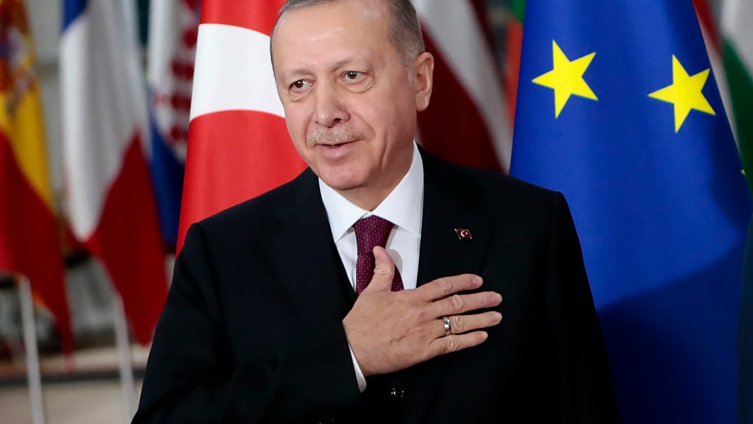 Turkish President Recep Tayyip Erdogan puts his hand over his heart in a gesture of hello prior to a meeting with European Council President Charles Michel.