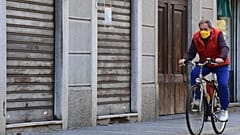 A resident  rides a bicycle past closed shops in a deserted street of central Codogno,  (Photo by Miguel MEDINA / AFP)