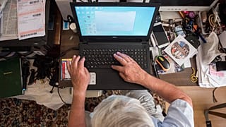 Otthonában laptopozik egy magyar férfi