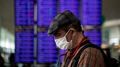 A man looks at his phone in front of the information screen at Barcelona airport, Spain, Thursday, March 12, 2020