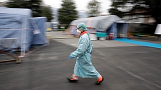 A staffer walks at one of the emergency structures that were set up to ease procedures at the Brescia hospital, northern Italy, Thursday, March 12, 2020.