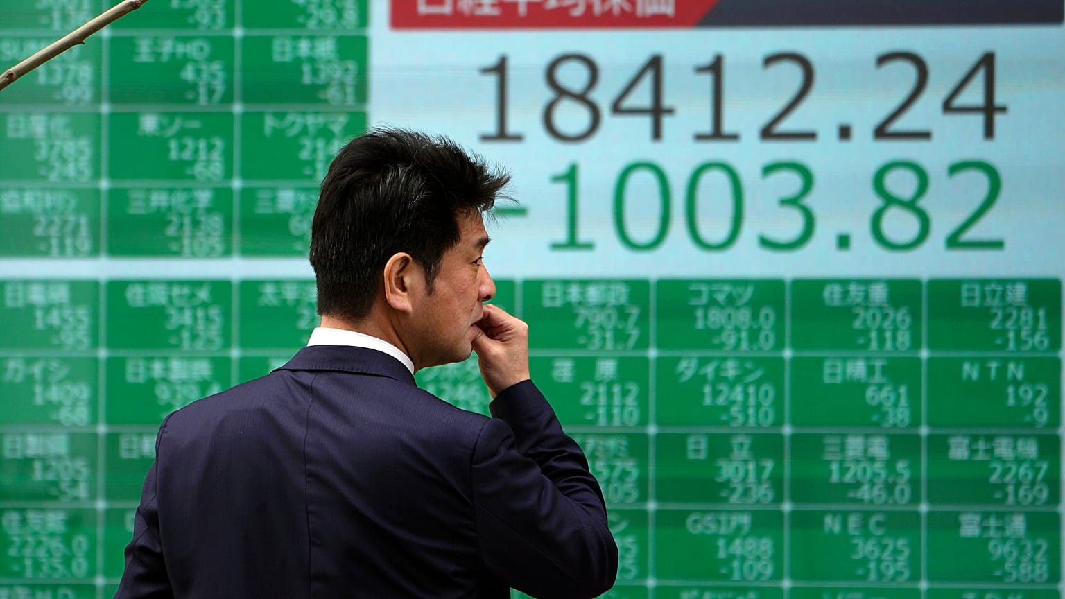 A man looks at an electronic stock board showing Japan's Nikkei 225 index at a securities firm in Tokyo Thursday, March 12, 2020. 
