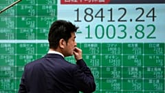 A man looks at an electronic stock board showing Japan's Nikkei 225 index at a securities firm in Tokyo Thursday, March 12, 2020. 