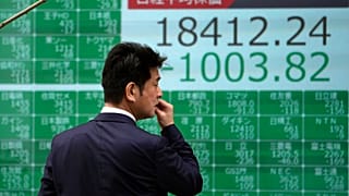 A man looks at an electronic stock board showing Japan's Nikkei 225 index at a securities firm in Tokyo Thursday, March 12, 2020. 