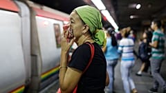 A woman covers her mouth and nose with a wash cloth on a subway platform in Caracas, Venezuela, Friday, March 13, 2020. 