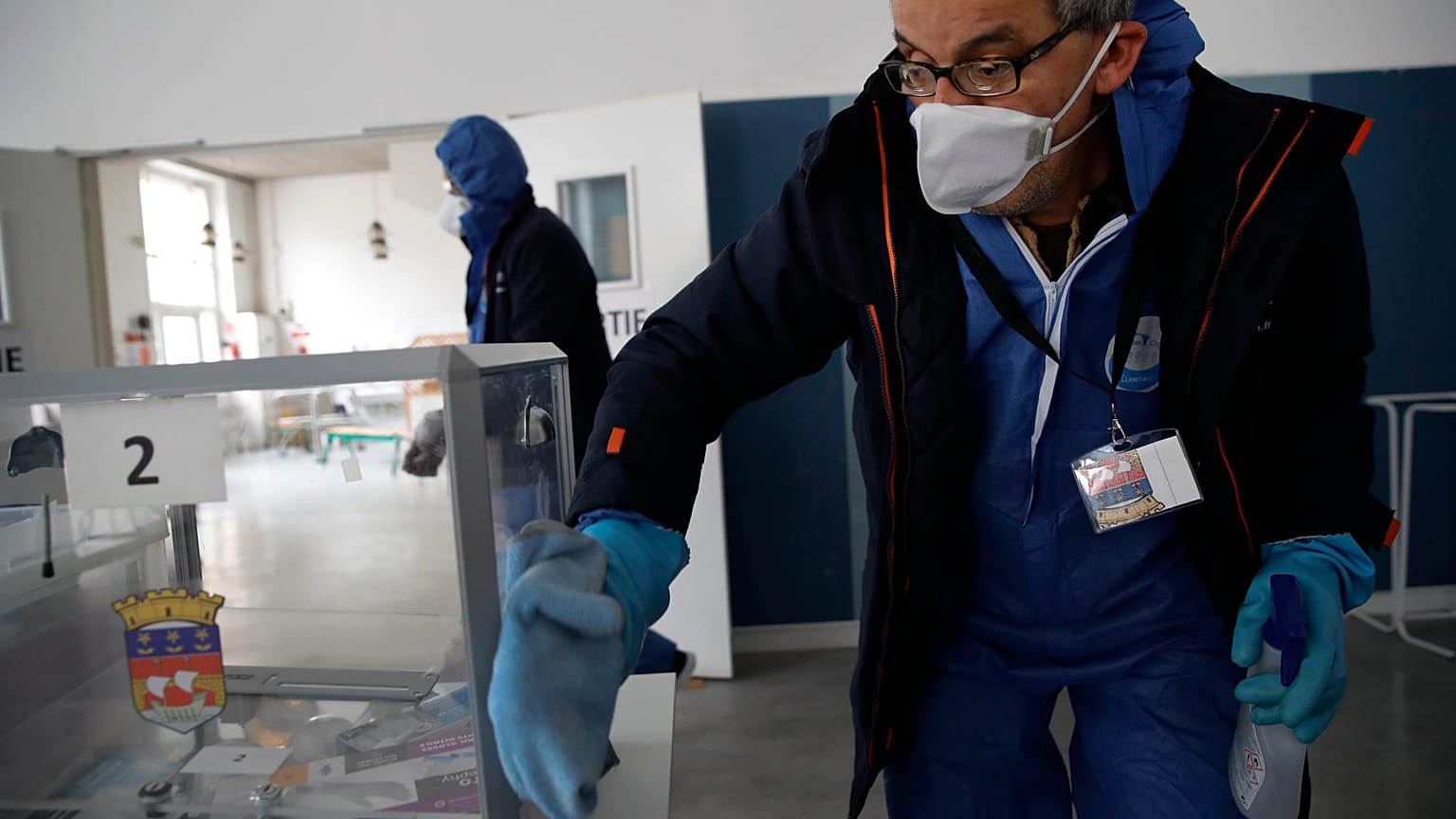 A worker wearing protective gears uses disinfectant to clean a polling box as a precautionary measure against COVID-19 on the eve of the municipal elections.