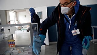 A worker wearing protective gears uses disinfectant to clean a polling box as a precautionary measure against COVID-19 on the eve of the municipal elections.