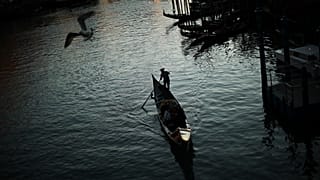 In this Feb. 28, 2020, file photo, a gondolier travels through the Grand Canal as the sun sets in Venice, Italy.