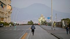 Un hombre haciendo deporte en las calles de Nápoles, frente al Vesubio, en plena cuarentena 