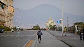 Un hombre haciendo deporte en las calles de Nápoles, frente al Vesubio, en plena cuarentena