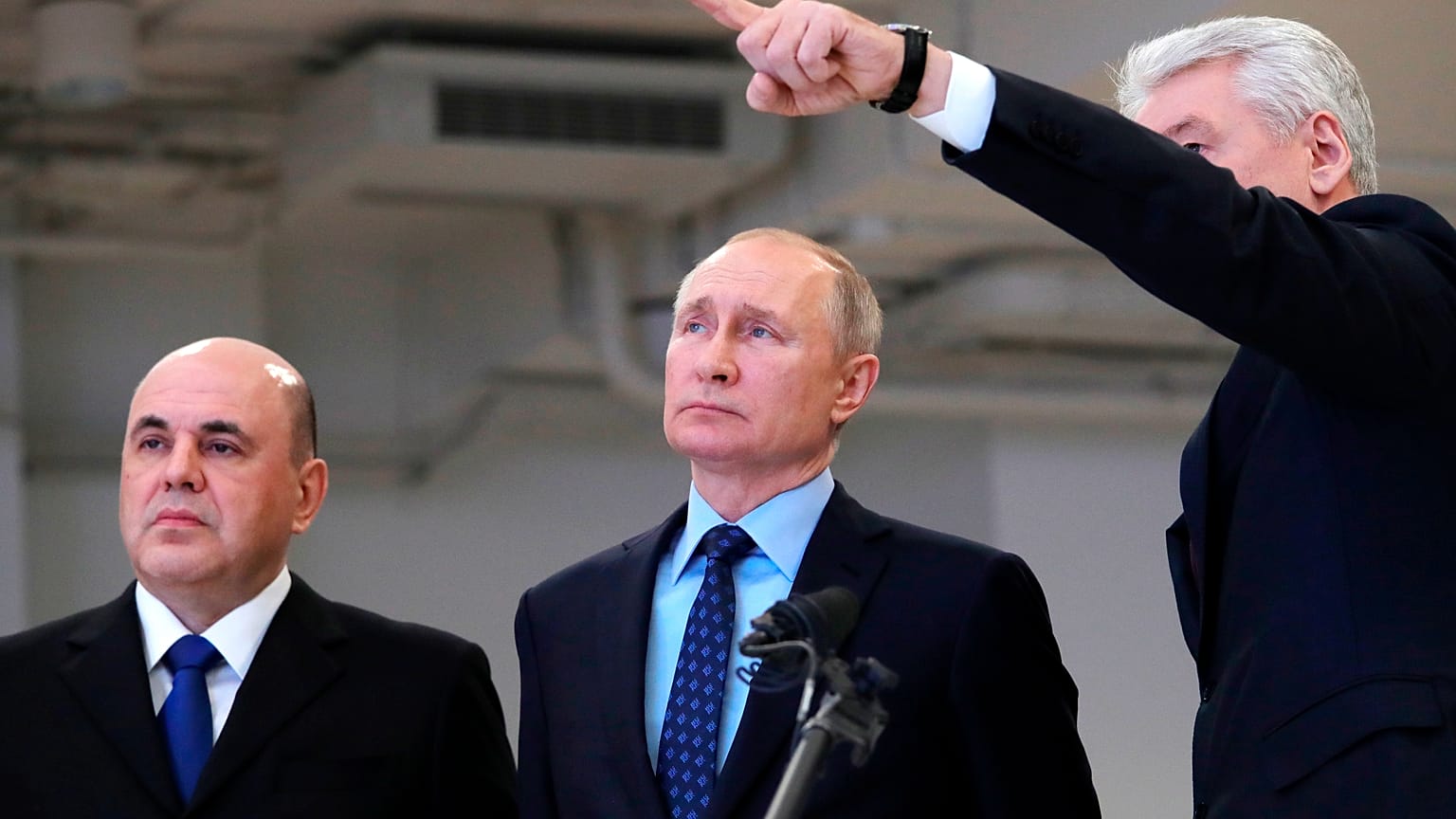 Moscow Mayor Sergei Sobyanin, right, points as he speaks to Russian President Vladimir Putin, center, and Prime Minister Mikhail Mishustin, left,.