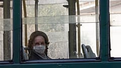 A woman wears a protective mask as she rides in a tram, in Rome, Wednesday, March 18, 2020. 