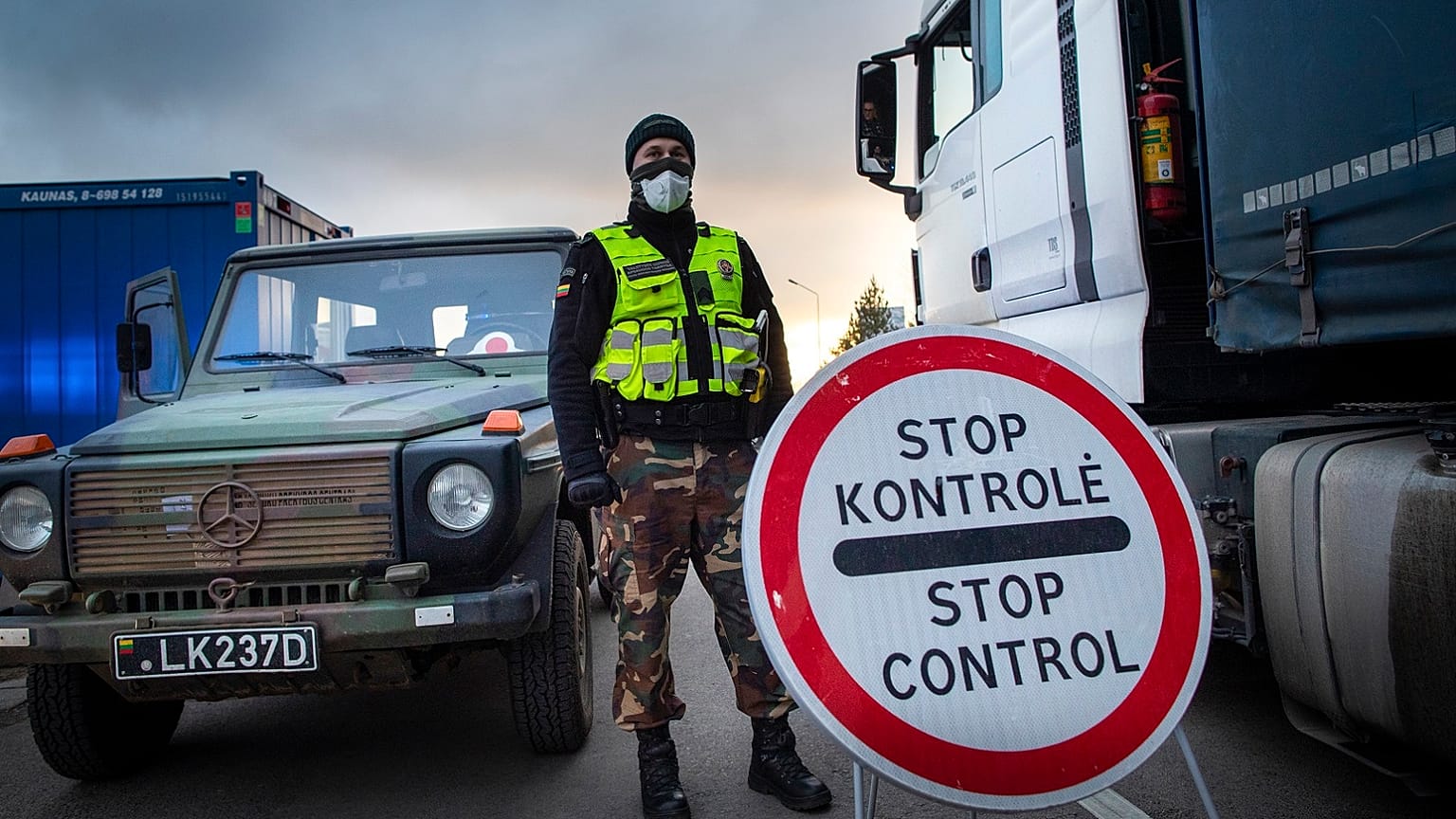 A Lithuanian border guard stands next to trucks stuck in traffic jams for 60 kilometers on Lithuanian side to enter Poland through Kalvarija-Budzisko check point