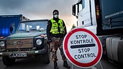 A Lithuanian border guard stands next to trucks stuck in traffic jams for 60 kilometers on Lithuanian side to enter Poland through Kalvarija-Budzisko check point
