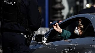 A police officer controls a man in Paris on March 19, 2020. (Photo by PHILIPPE LOPEZ / AFP)