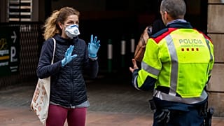 Una mujer habla con un policía en Barcelona, España, el miércoles 18 de marzo de 2020.