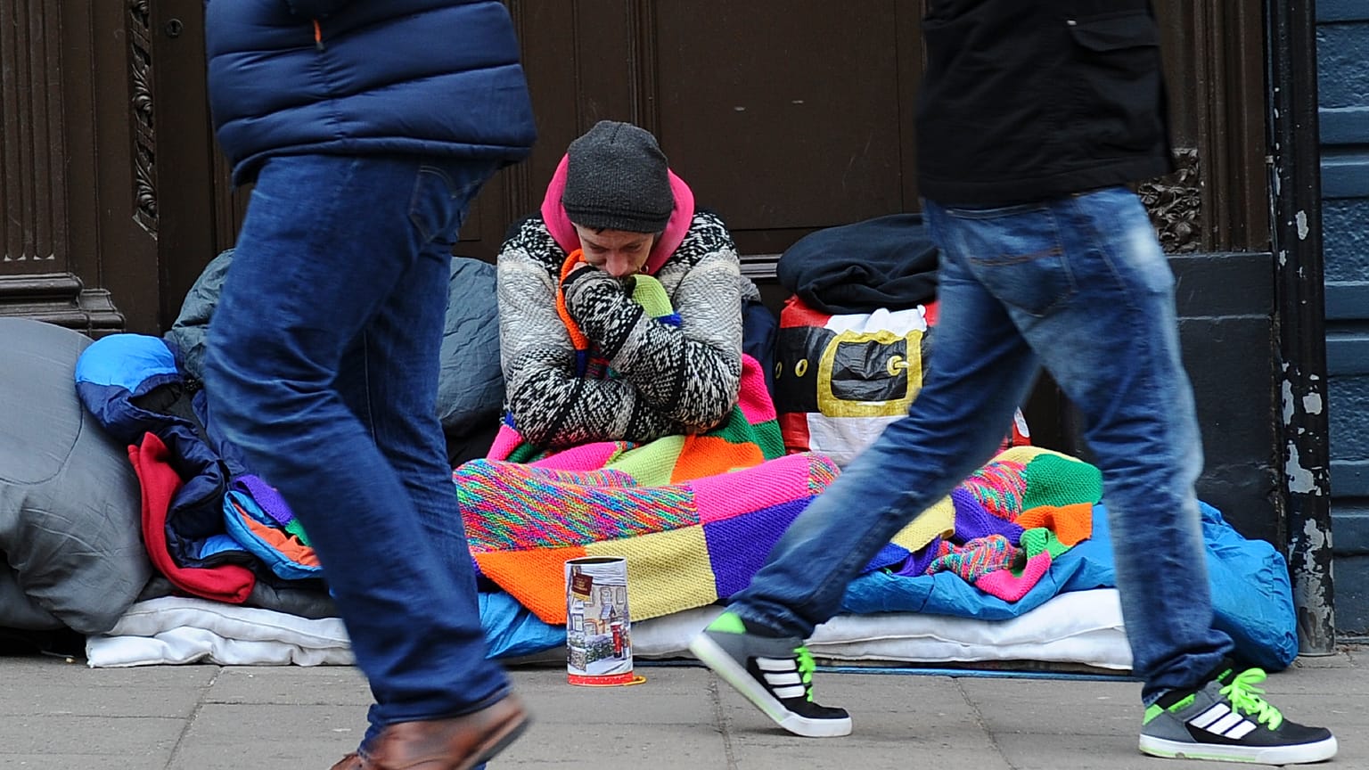 Pedestrians walk past a homeless man in the UK.