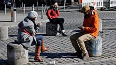People sit on the bollards on the Admiral Bridge in Berlin's Kreuzberg district on March 22, 2020, amidst the new coronavirus COVID-19 pandemic. (Photo by David GANNON / AFP)