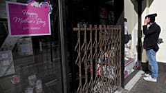 A man looks into a closed shop selling Mother's day gifts in London, Sunday, March 22, 2020.
