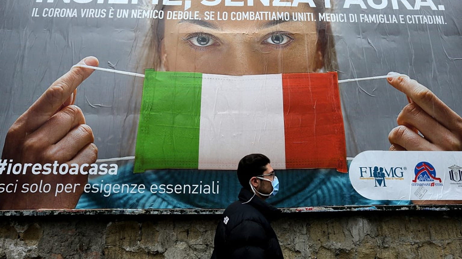 A man walks past a large billboard raising awareness to the measures  