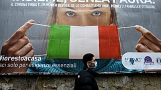 A man walks past a large billboard raising awareness to the measures  