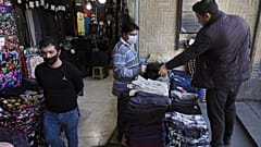 A shopkeeper, center, wearing a face mask and gloves, to help protect against the new coronavirus, talks with his customer at the Tehran's Grand Bazaar, Iran