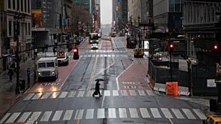A commuter crosses 42nd Street in front of Grand Central Terminal during morning rush hour, Monday, March 23, 2020, in New York