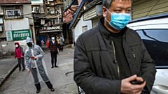 Des habitants font la queue pour acheter du porc à l'entrée de leur résidence, le 18 mars à Wuhan en Chine