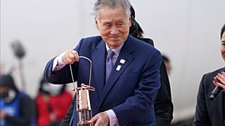 In this March 20, 2020, file photo, Japanese comedians Mikio Date, foreground, and Takeshi Tomizawa leave with the Olympic flame in northern Japan.