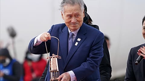 In this March 20, 2020, file photo, Japanese comedians Mikio Date, foreground, and Takeshi Tomizawa leave with the Olympic flame in northern Japan.