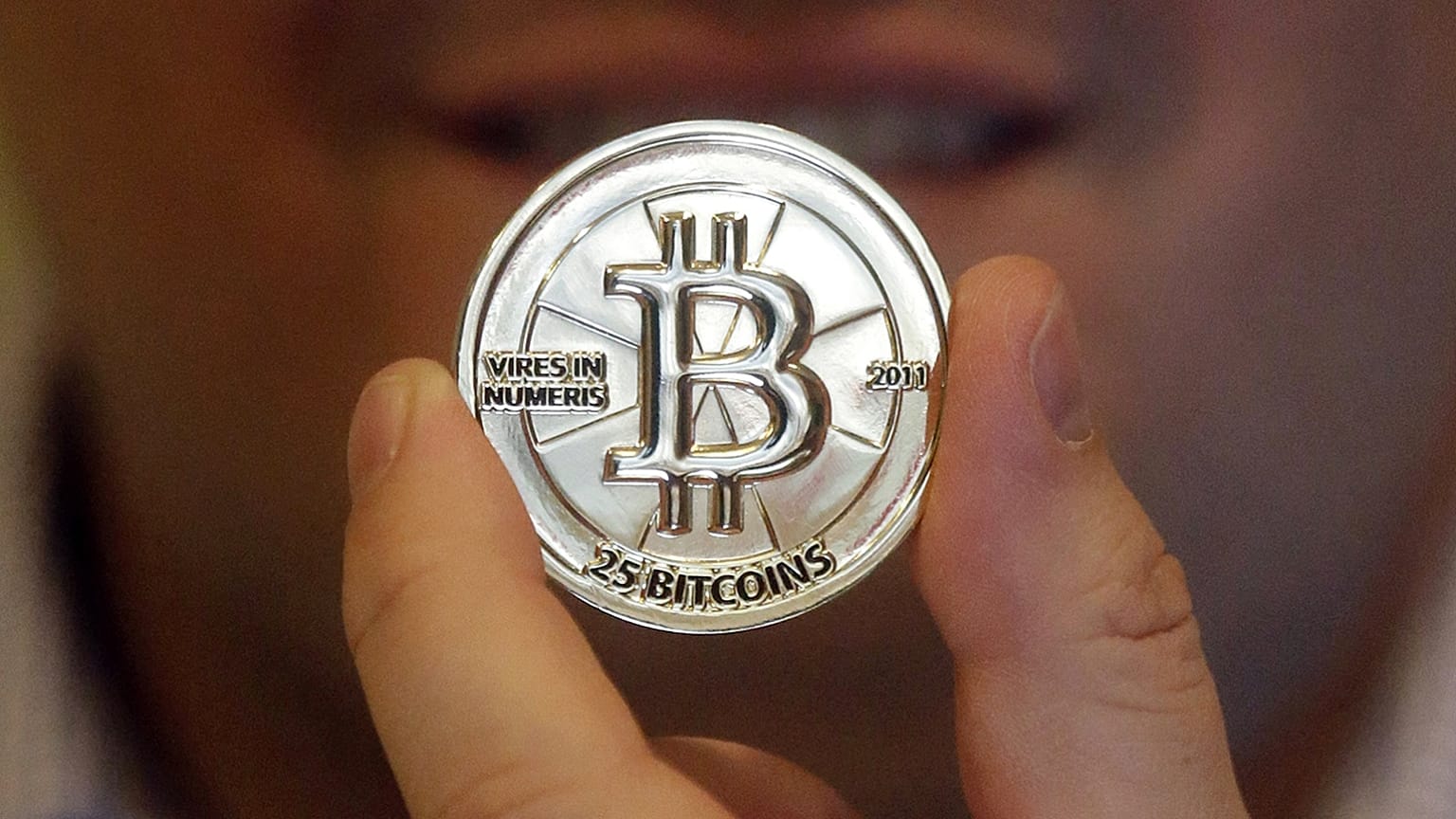 In this April 3, 2013 photo, Mike Caldwell, a 35-year-old software engineer, holds a 25 Bitcoin token at his shop in Sandy, Utah