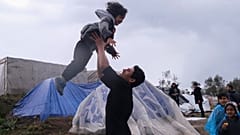 Migrants play next to their makeshift tents outside the perimeter of the overcrowded Moria refugee camp on the northeastern Aegean island of Lesbos, Greece