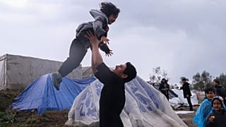 Migrants play next to their makeshift tents outside the perimeter of the overcrowded Moria refugee camp on the northeastern Aegean island of Lesbos, Greece