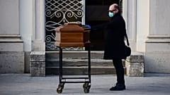 A man touches the coffin of his mother during a funeral service in the closed cemetery of Seriate, near Bergamo